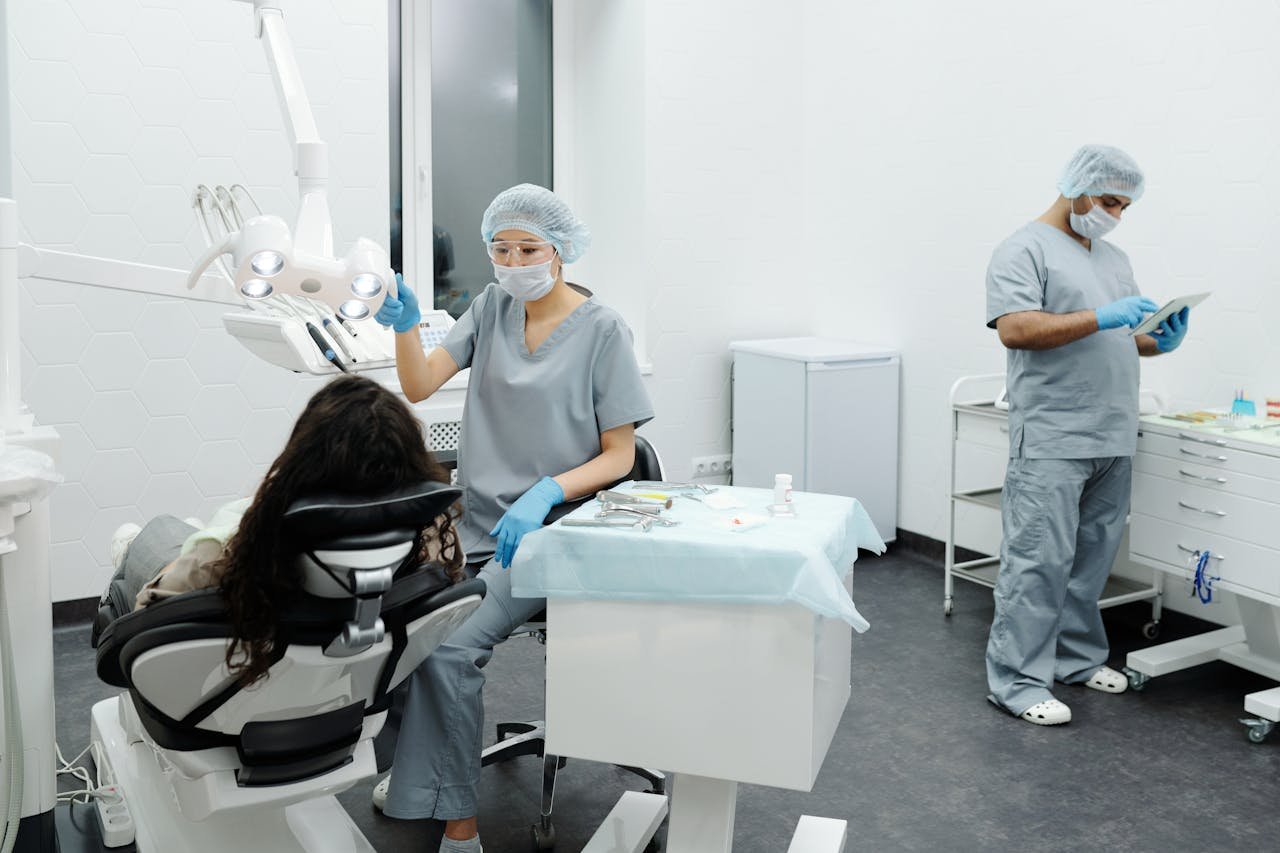 A dentist and assistant in a clinic attending to a patient with professional care.